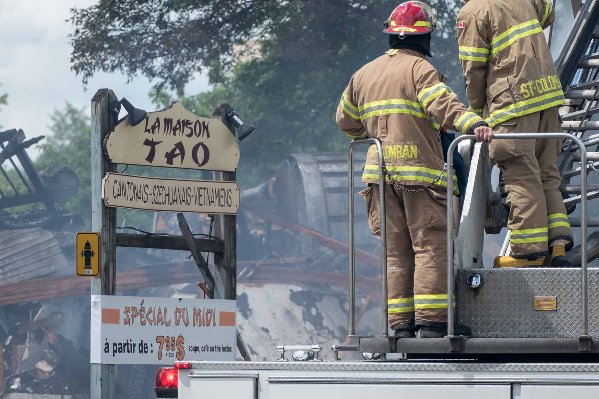 Des pompiers de Saint-Colomban arrosent les débris d'un édifice en démolition sur la rue Labelle, au centre-ville de Saint-Jérôme le 27 juin 2017.